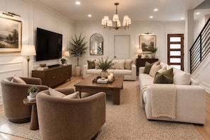 A living room with a flat-screen TV, a wooden coffee table, and two sofas. - 5BR Trinity Groves w/ Pool & Jacuzzi (Dallas)