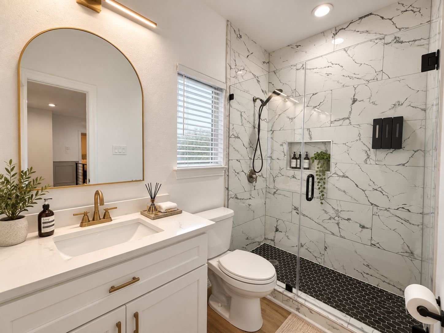 A bathroom with a white vanity, a large mirror, a shower with a glass door, and marble walls.