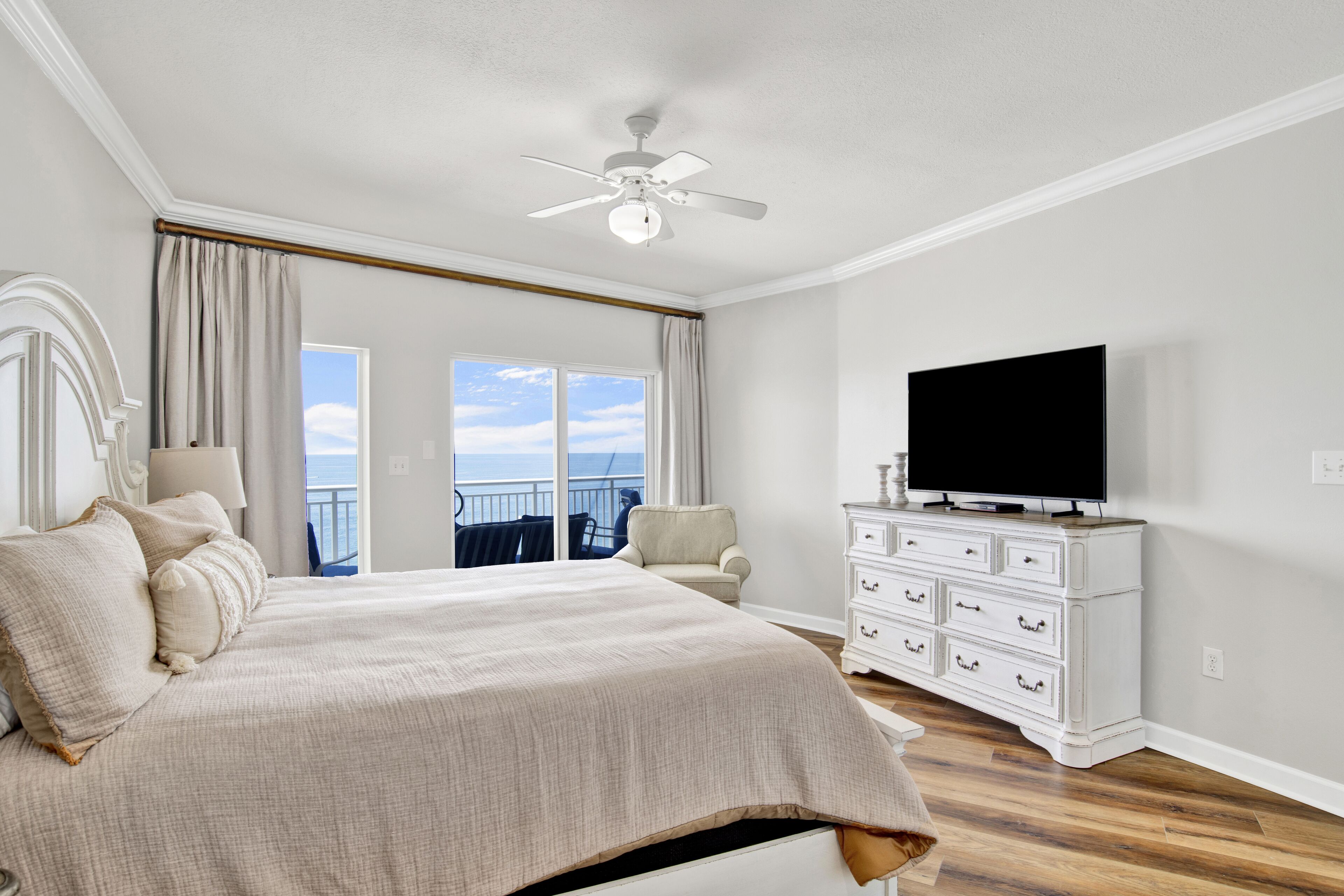 Una camera da letto con un letto grande, una televisione su un comò e un balcone con vista.