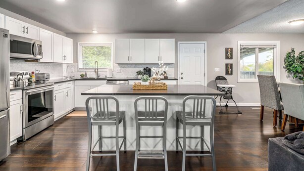 A modern kitchen with white cabinets, stainless steel appliances, and a central island with bar stools.