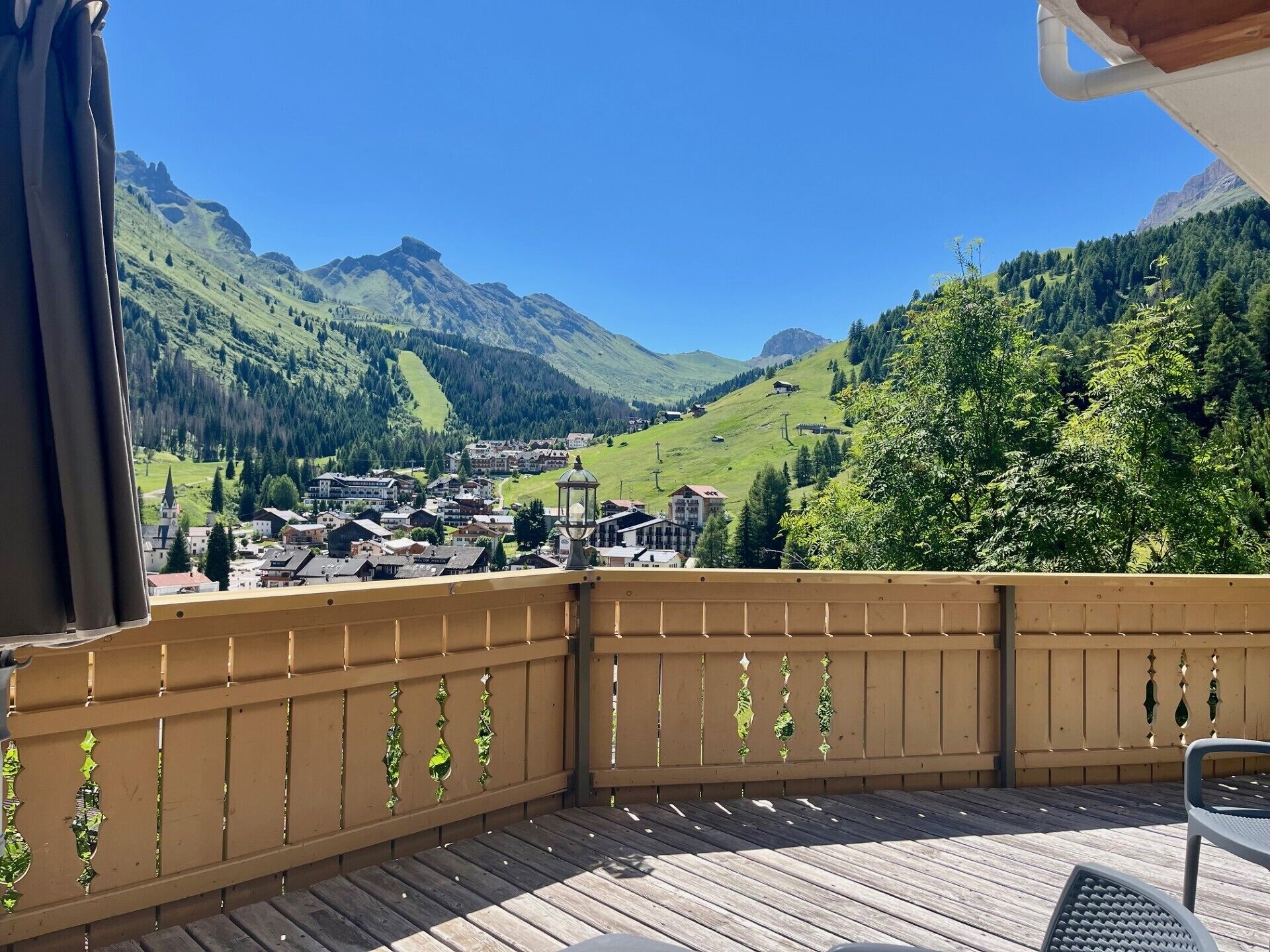 A balcony with a wooden floor and a view of a mountain town with houses and a church.