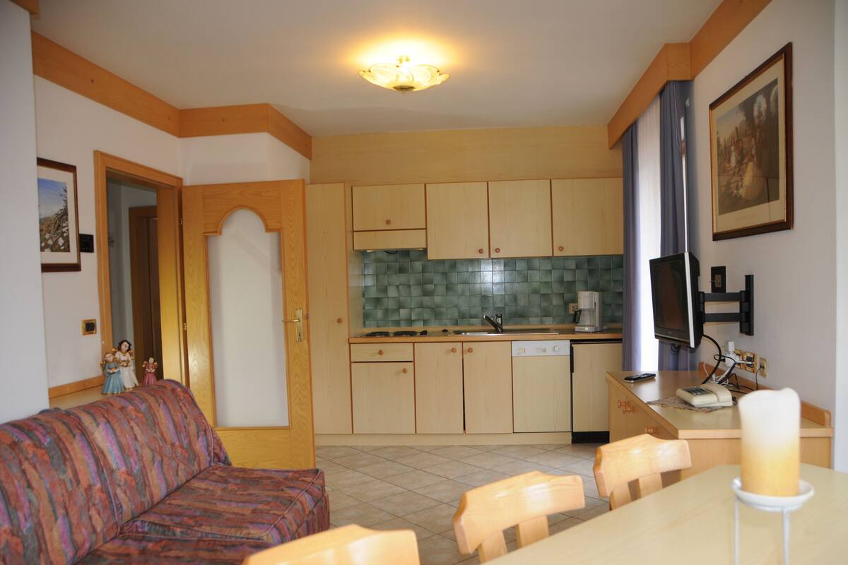A compact kitchen with wooden cabinets, a tiled backsplash, and a dining area with a table and chairs.