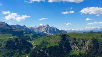 A mountainous landscape with a winding road, green fields, and a small settlement.