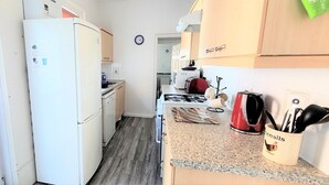 A compact kitchen with white appliances, a granite countertop, and a mug labeled "towels".