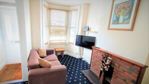 A living room with a sofa, a small table, a fireplace, and a TV.