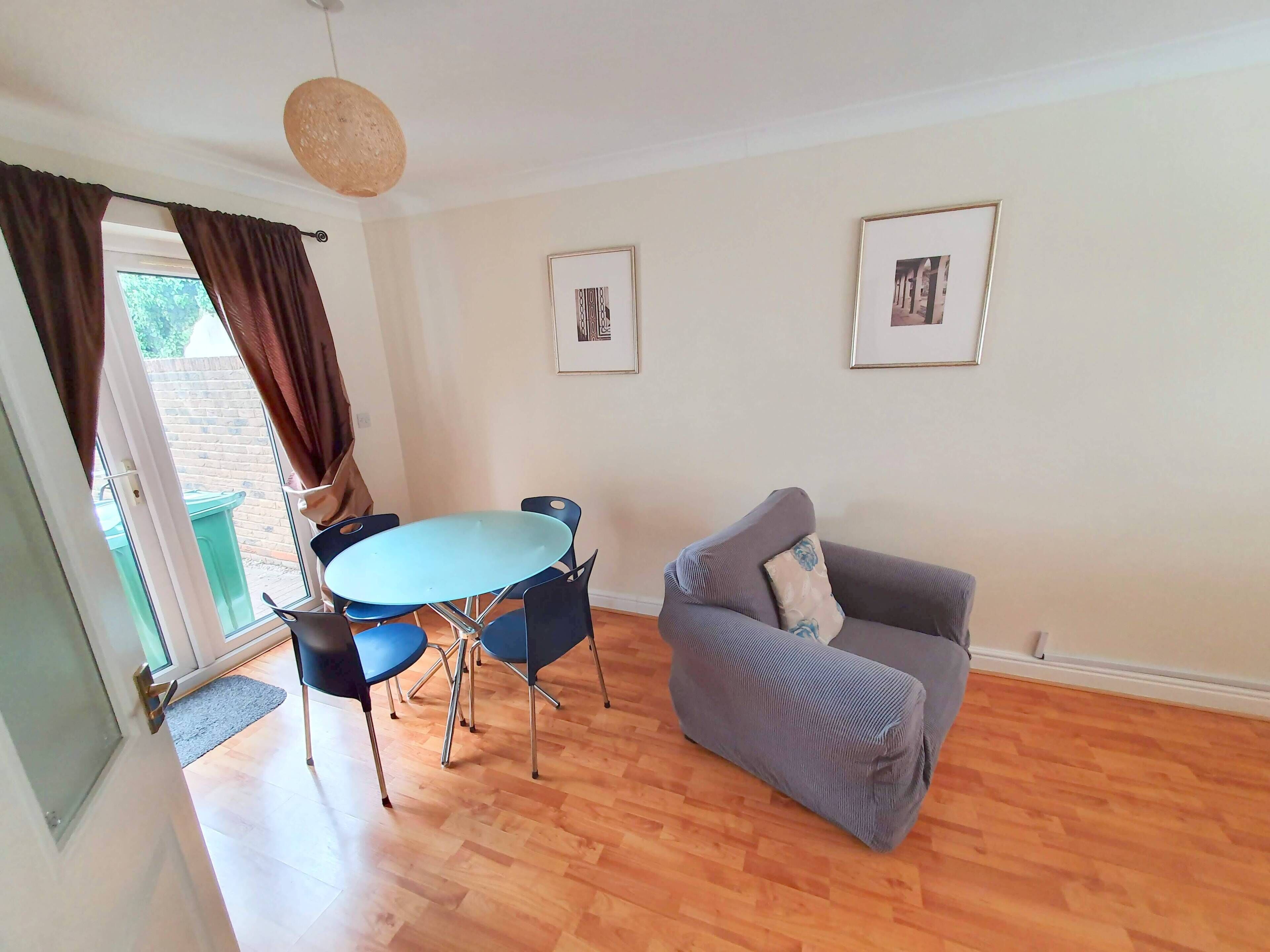 A living room with a round table, blue chairs, a grey sofa, and two framed pictures on the wall.