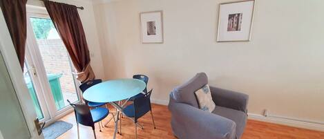 A living room with a round table, blue chairs, a grey sofa, and two framed pictures on the wall.