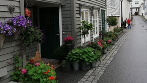 Eine enge Straße gesäumt von traditionellen Gebäuden, mit Balkonen, die mit Blumentöpfen und Blumen geschmückt sind.