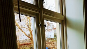 Ein Fenster mit Blick auf eine Steinmauer und einen Baum.