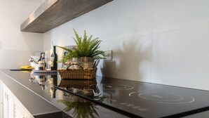 Une cuisine moderne avec un plan de travail noir, un panier contenant une plante et une bouteille de vin.