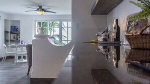 Une cuisine moderne avec un îlot central blanc, un ventilateur de plafond et une fenêtre donnant sur des palmiers.