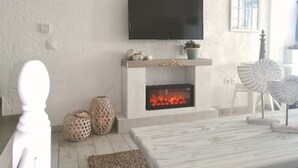 A living room with a fireplace, a mounted TV, and decorative items. - House by the sea with amazing view (Skala Fourkas)