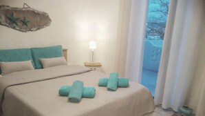 A bedroom with a bed, two pillows, a nightstand with a lamp, and a view of the outdoors. - House by the sea with amazing view (Skala Fourkas)