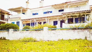 A white building with multiple balconies and blue shutters, surrounded by a grassy area. - House by the sea with amazing view (Skala Fourkas)