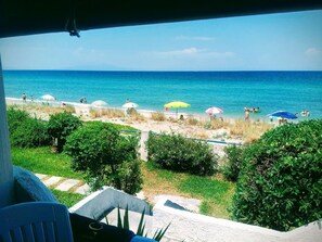 Une plage avec vue sur la mer, des parasols et des gens.