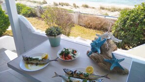 A table with plates of fish and salad, a potted plant, and decorative sea shells. - House by the sea with amazing view (Skala Fourkas)