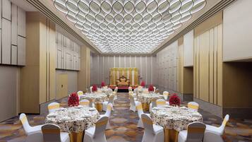 A banquet hall with round tables, white chairs, and a central stage.