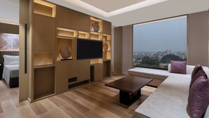 A modern living room with a flat-screen TV, built-in shelves, a sofa, and a coffee table. - Courtyard by Marriott Amritsar (Amritsar)