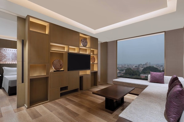 A modern living room with a flat-screen TV, built-in shelves, a sofa, and a coffee table. - Courtyard by Marriott Amritsar (Amritsar)