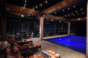 Un espace piscine sur le toit, avec des chaises longues et un bar.