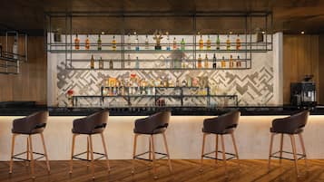 Angolo bar con soffitto in legno, parete a motivi a zigzag e bancone con sgabelli.