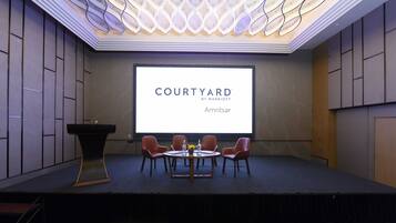 Ein Konferenzraum mit einer großen Leinwand, die 'COURTYARD BY MARRIOTT Amritsar' anzeigt.