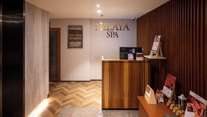 A reception area with a wooden reception desk, a sign reading "NILAYA SPA", and a herringbone-patterned floor. - Courtyard by Marriott Amritsar (Amritsar)