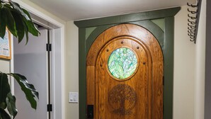A wooden front door with a stained glass window, a doormat, and a ceiling-mounted light fixture.