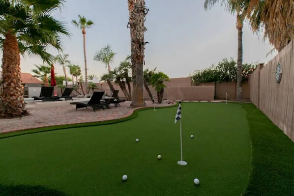 Een minigolfbaan met een groene puttingzone, een vlag en een paar golfballen.