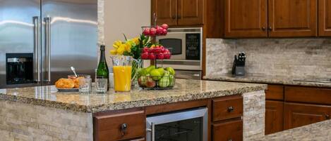 A kitchen with granite countertops, wooden cabinets, a stainless steel refrigerator, a microwave, and a built-in oven.