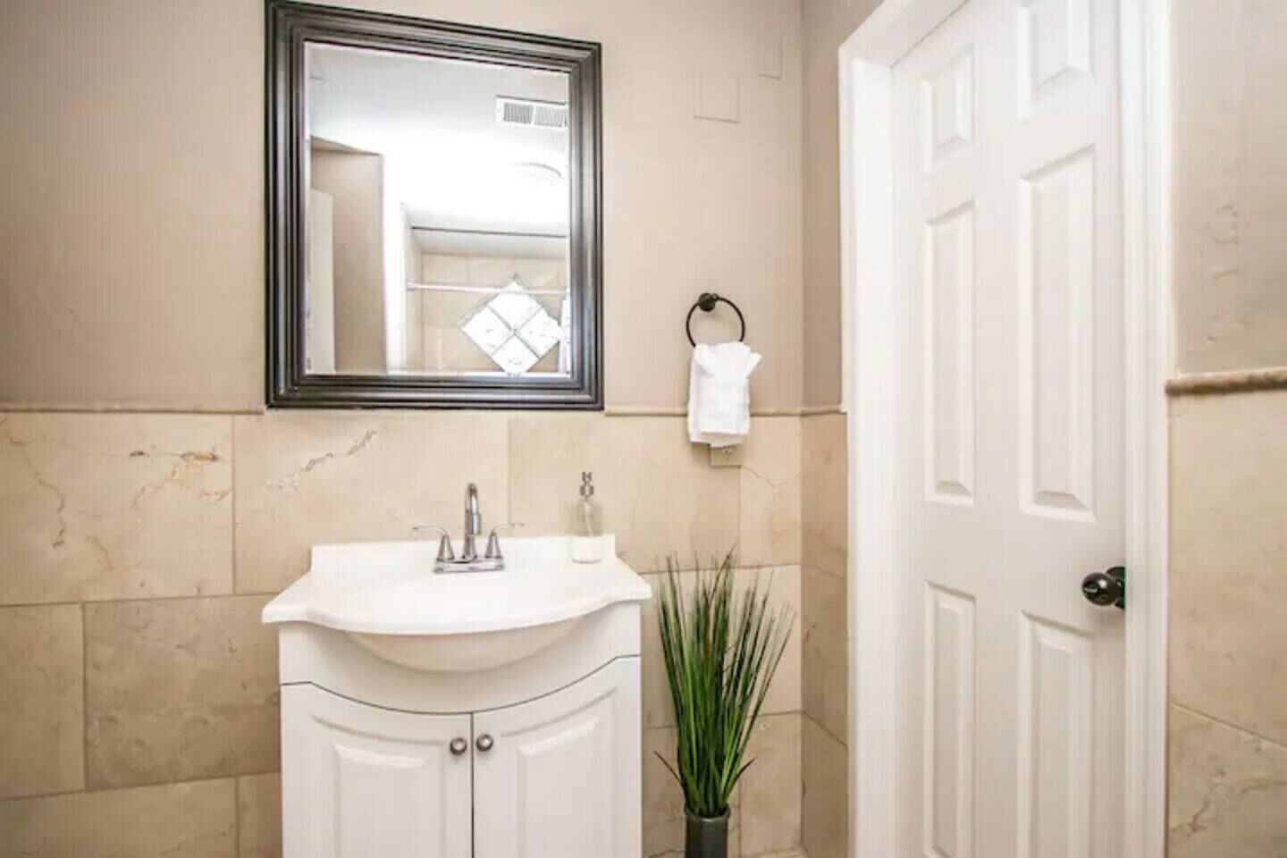 A bathroom with a white sink, a mirror, a towel rack, and a door.
