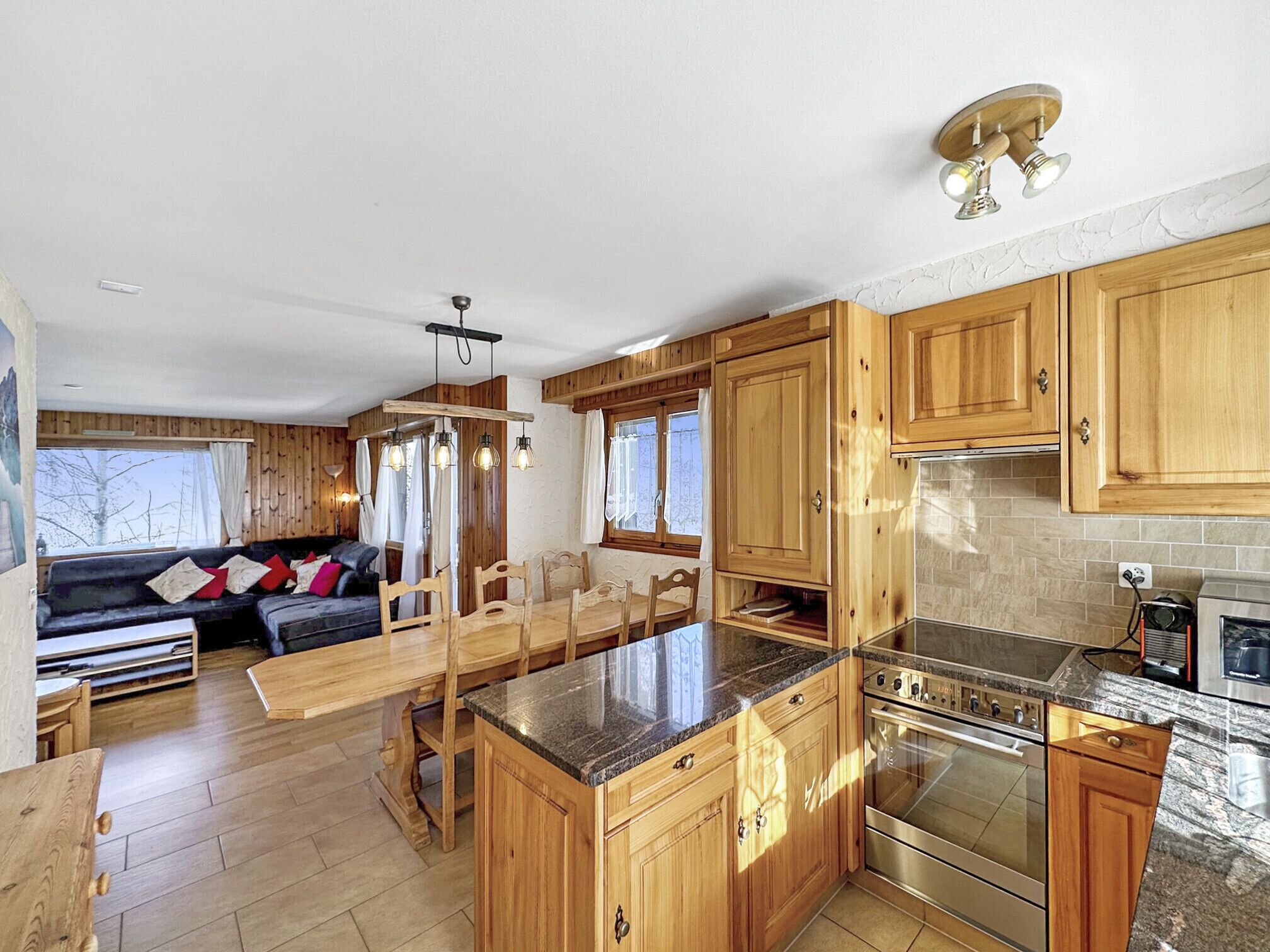 A modern kitchen with wooden cabinets, a granite countertop, and stainless steel appliances.
