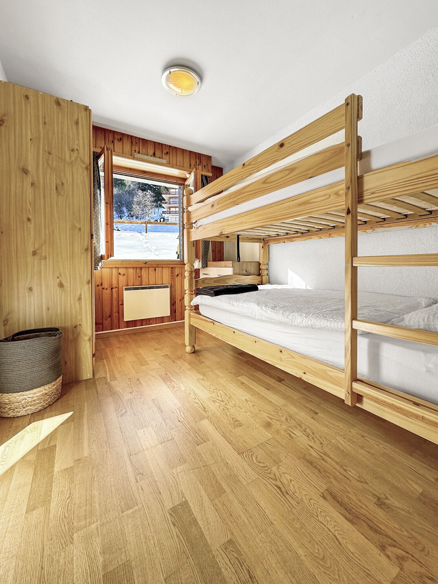 Une chambre avec un lit superposé, des murs en bois et une fenêtre.