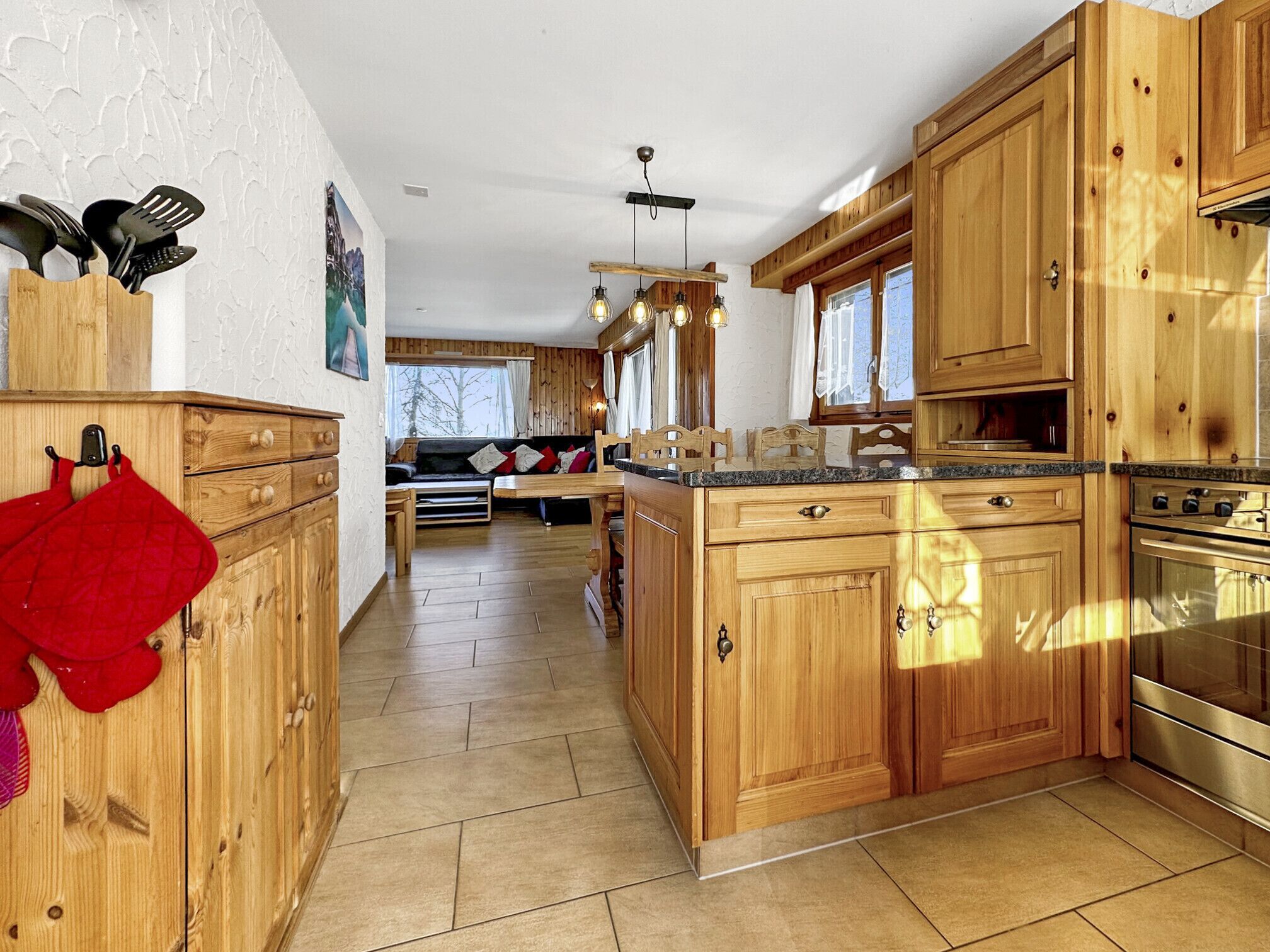 Een ruime keuken met houten kastjes, een centraal eiland en een inbouwoven.
