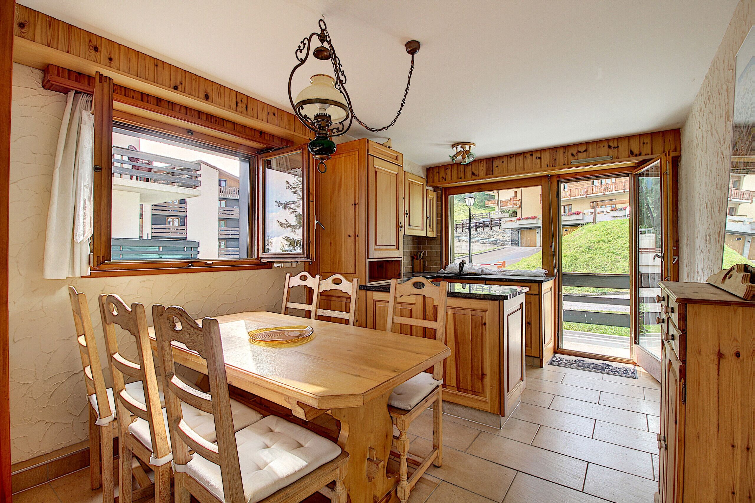 A wooden interior with a dining table, chairs, and a kitchen area.