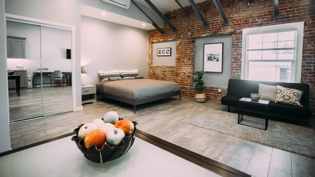 A modern bedroom with a brick wall, a bed, a sofa, and a coffee table. - Loft apartment in Hollywood (Los Angeles)
