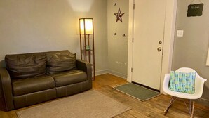 A living room with a brown leather sofa, a white chair, a floor lamp, and a star decoration on the wall.