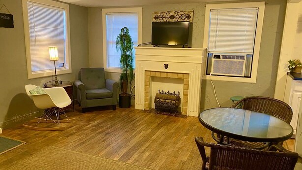 A living room with a fireplace, a television, a dining table, and two chairs.