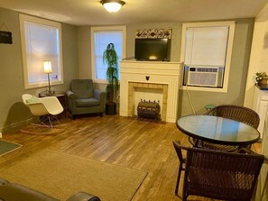 A living room with a fireplace, a television, a dining table, and two chairs.