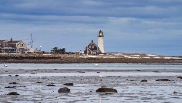 A coastal scene with a lighthouse, a building, and a rocky shoreline. - Oceanfront Beach House/ Fall asleep listening to the waves (Scituate)