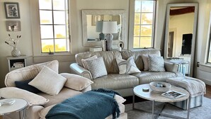 A spacious living room with a large sectional sofa, a round coffee table, and a fireplace. - Oceanfront Beach House/ Fall asleep listening to the waves (Scituate)