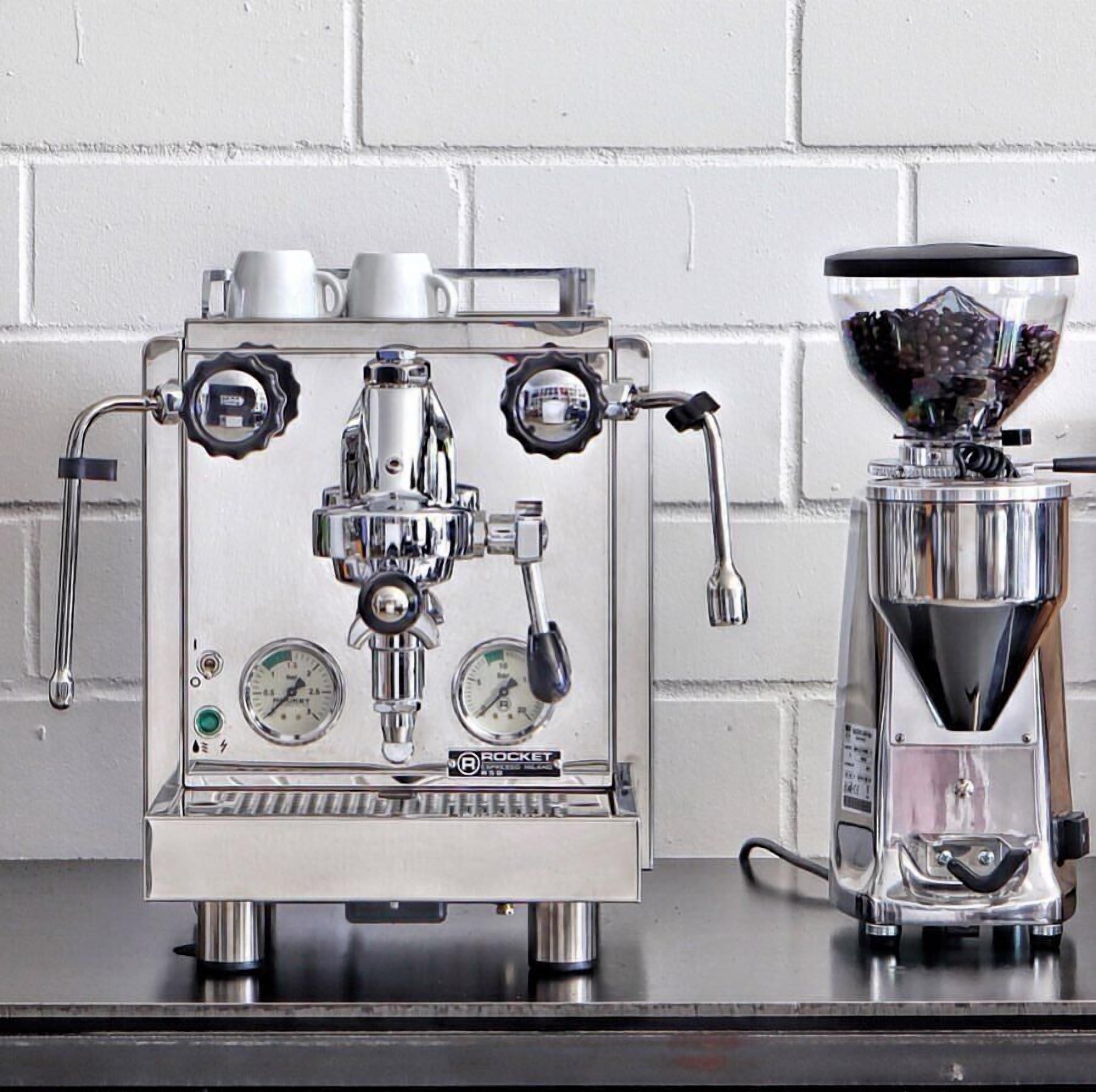 Una máquina de espresso de acero inoxidable con dos indicadores de presión, una boquilla de vapor y un portafiltro.