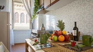 A kitchen with a fruit bowl, green mugs, and a bottle of wine on the counter. - St. Joseph apartment 47 (Roma)