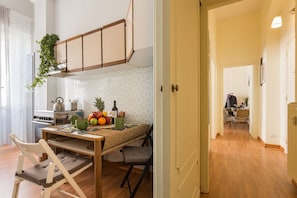 A modern kitchen with a dining area, wooden cabinets, and a hanging plant.