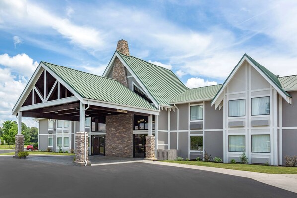 A modern hotel with a covered entrance, stone pillars, and a green roof. - Quality Inn Ocoee - Cleveland East (Ocoee)