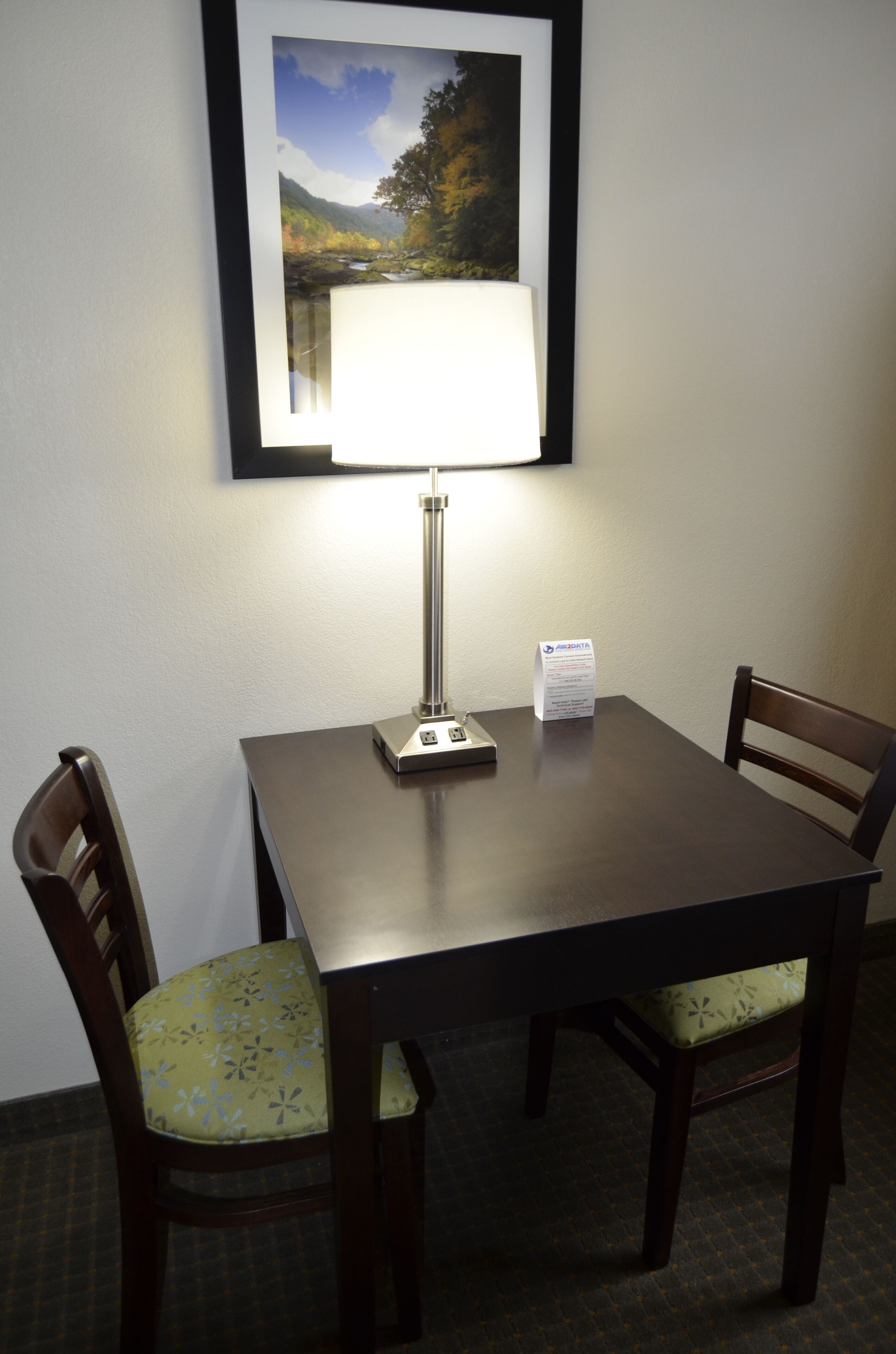 Een tafel met een lamp, een lijst met een afbeelding en een menukaart.