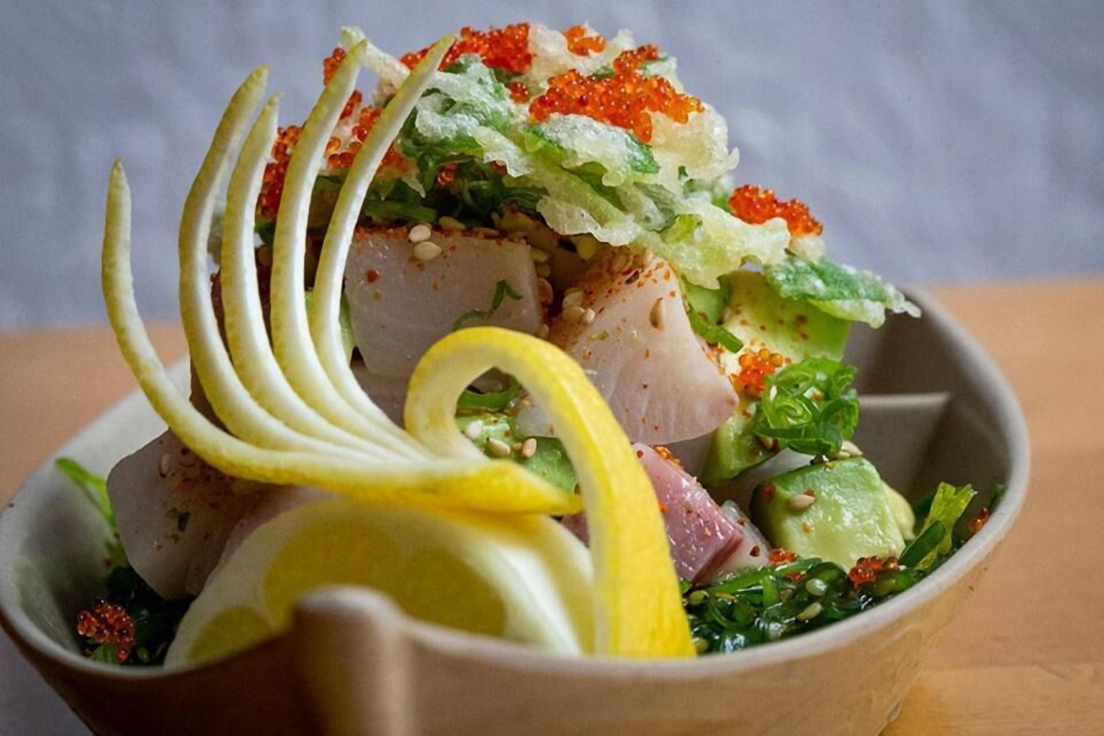 A bowl of food with various ingredients and garnishes.