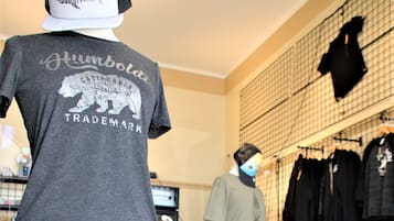 Loja de roupas com araras cheias de peças e um manequim exibindo uma camiseta.