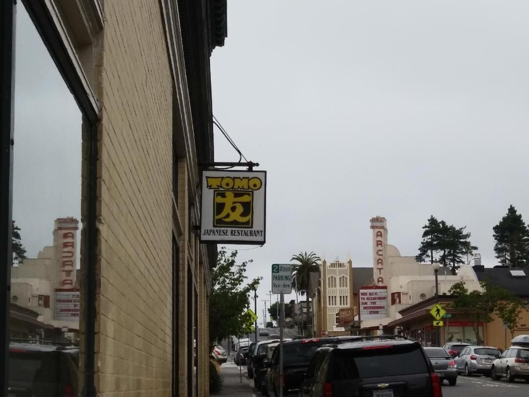 Vista de la calle con un letrero de restaurante japon és, coches estacionados y un edificio con el letrero "ARCATA".