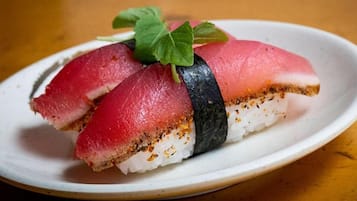 A plate with a sushi roll, including a slice of fish and a leaf garnish.